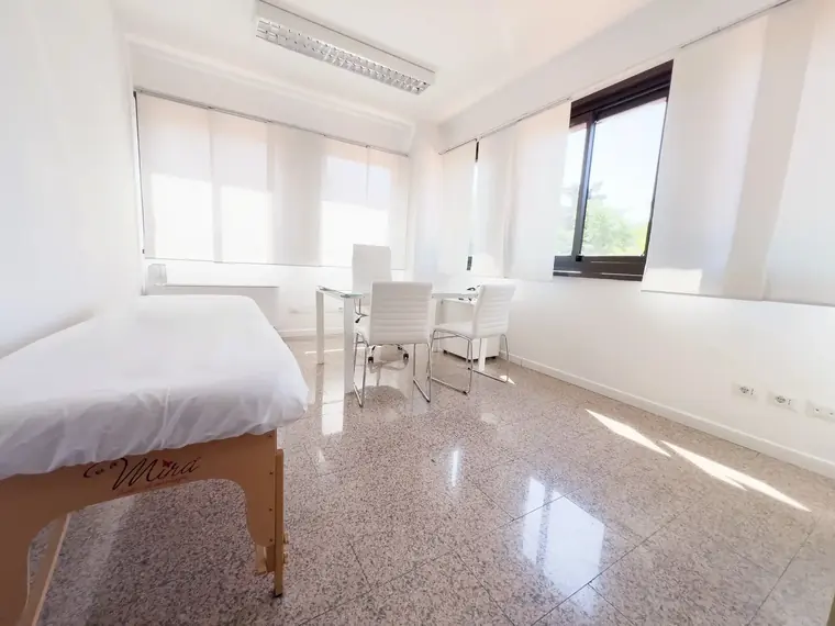Ufficio arredato luminoso con scrivania bianca e sedute per i clienti