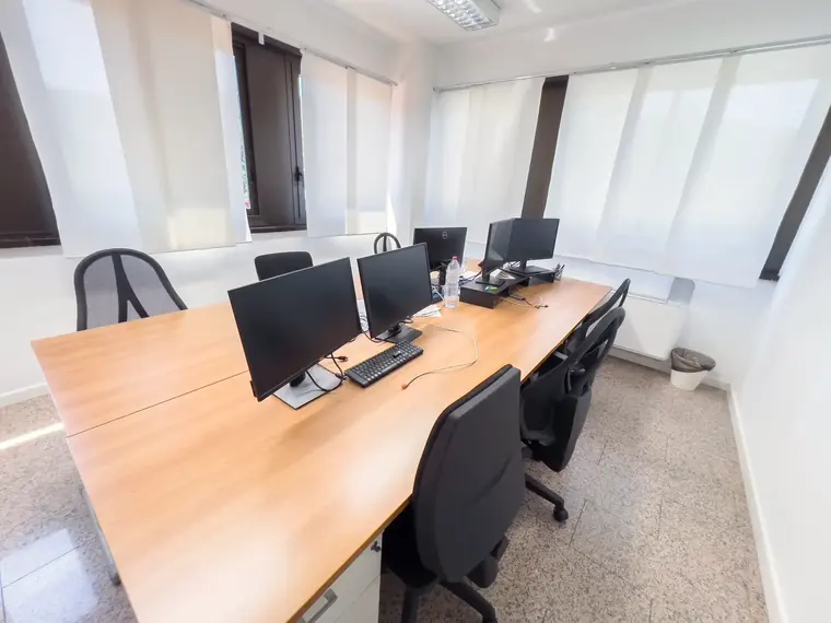 Open space con tavolo di lavoro in legno e postazioni