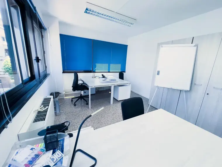 Sala con tavolo bianco e lavagna, pronta per un corso